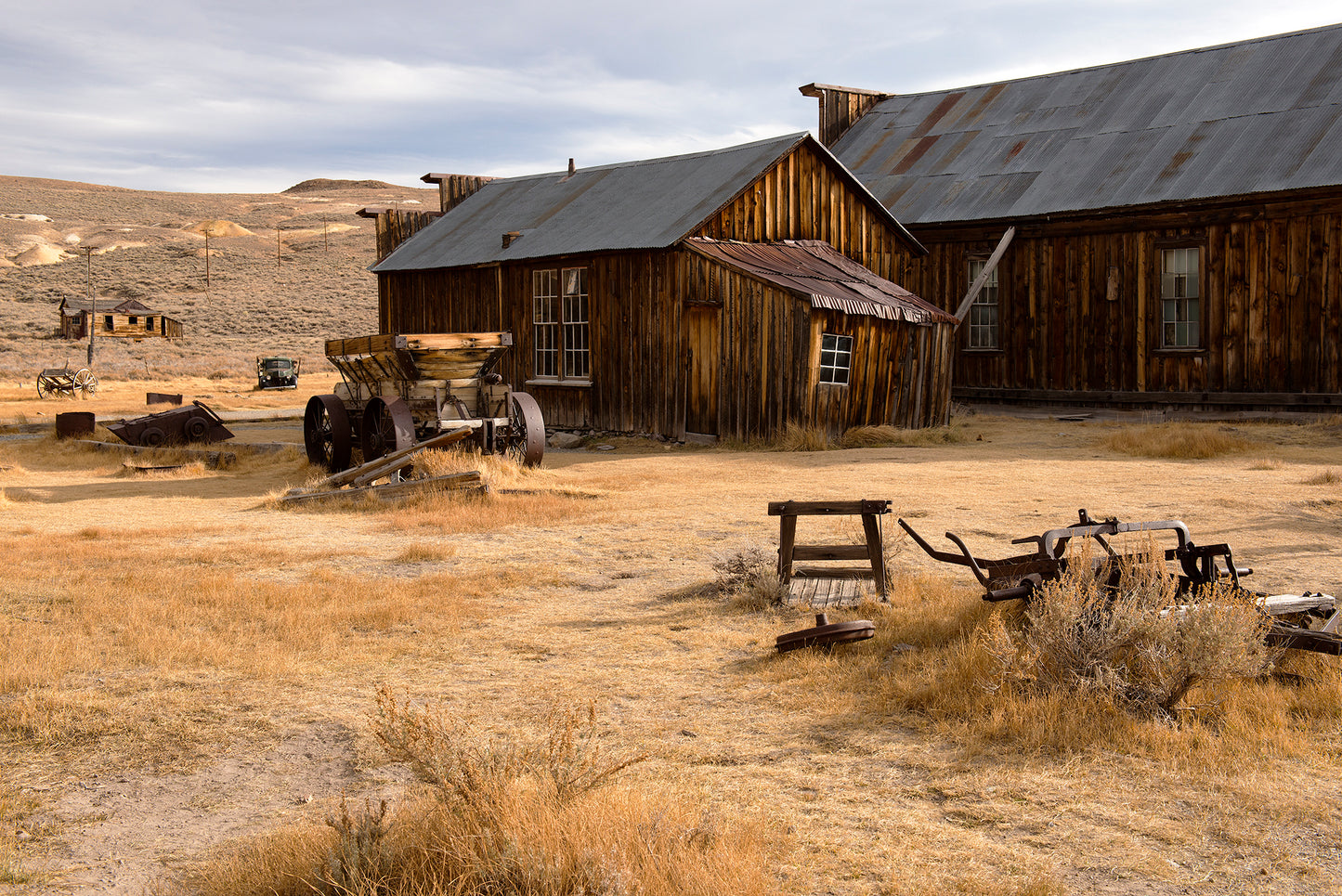Abandoned buildings and rusted relics in Bodie, California, captured on Halloween—weathered wood and dry grass evoke the eerie stillness of a ghost town.