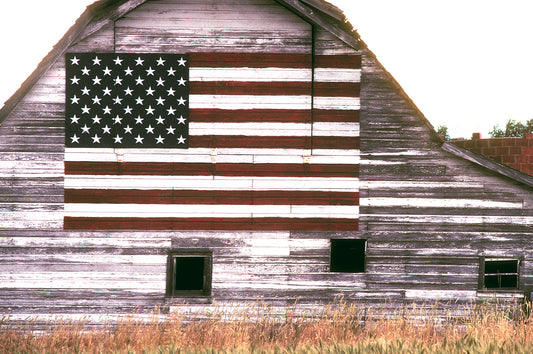 Weathered barn near Longmont, Colorado with a hand-painted American flag on the side, photographed on Kodachrome film during a summer lightning storm.