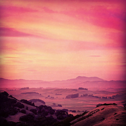 Vibrant summer sunset over rolling hills in Chileno Valley, with rich pink and gold tones, added texture, and vignetting enhancing the dramatic landscape.